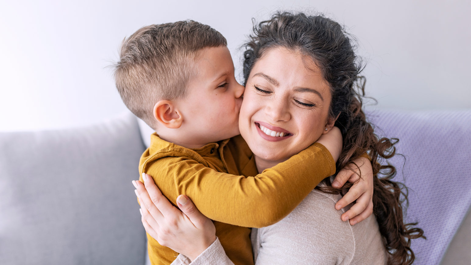 Щастлива майка получава целувка от малкия си син, израз на любов и семейна близост.